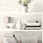 White shelves with decorative items against a patterned wallpaper.