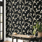 Wallpaper with floral pattern on a black background in a room with a wooden bench and plant.