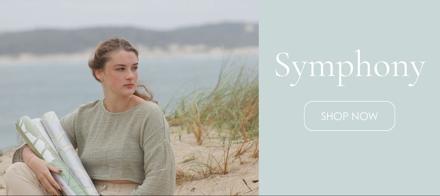 Woman holding rolled-up papers by a body of water with 'Symphony' branding.