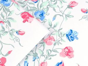 Charlotte Coral Pink Wallpaper features intertwined bunches of sweetpeas cast amongst scrolling tendrils and falling leaves and has a beautiful vintage feel